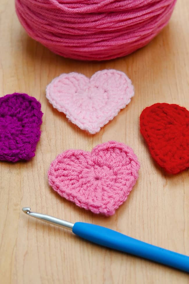 Easy Crochet Heart Pink and red crochet hearts beside supplies to make one