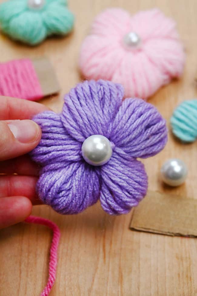 How to Make a Yarn Flower Holding a purple yarn flower