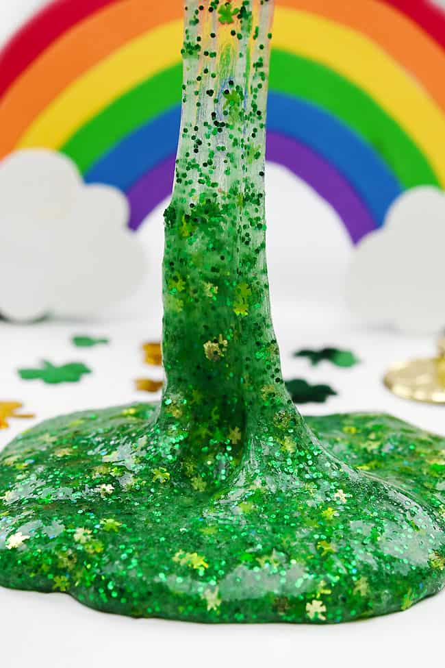 Stretching St. Patrick's Day slime up in front of a rainbow backdrop