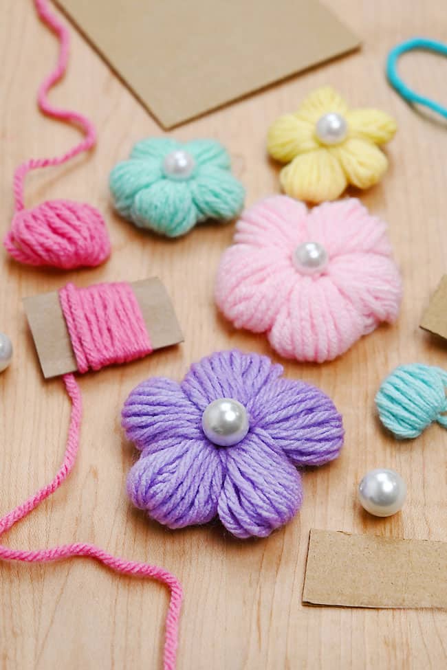 Yarn Flower Cardboard Cute flowers made with yarn beside craft supplies to make them