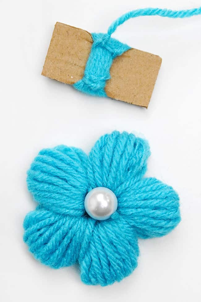 Yarn Flower Craft Blue yarn flower beside cardboard used to make the petals