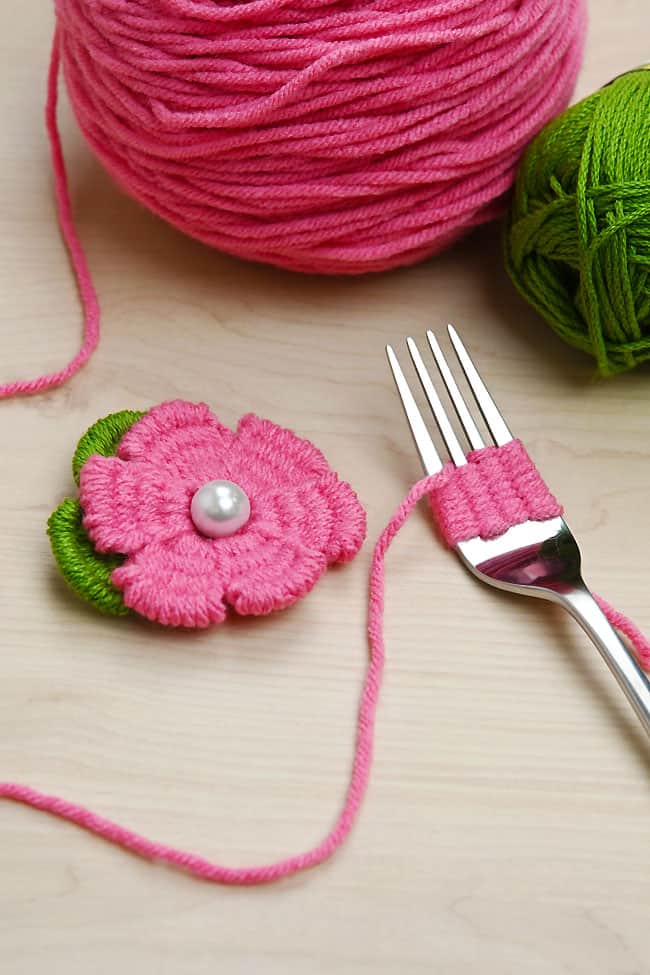 Fork Flower Craft Closeup on a pink yarn flower and a flower being made on a fork