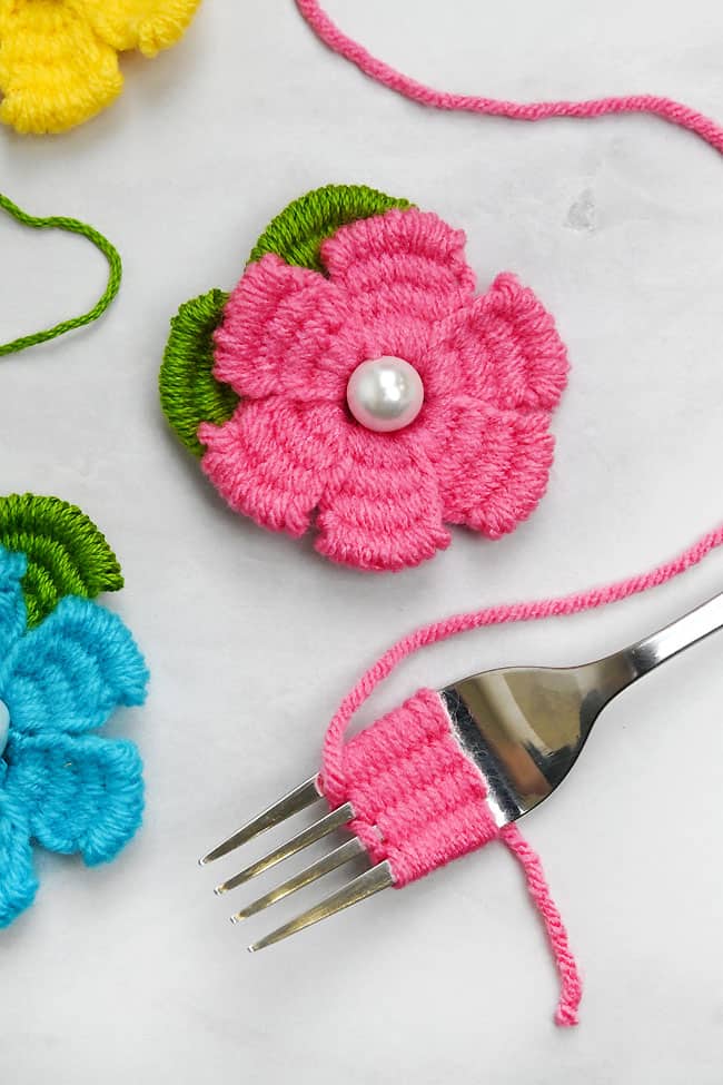Making a pink yarn flower on a fork