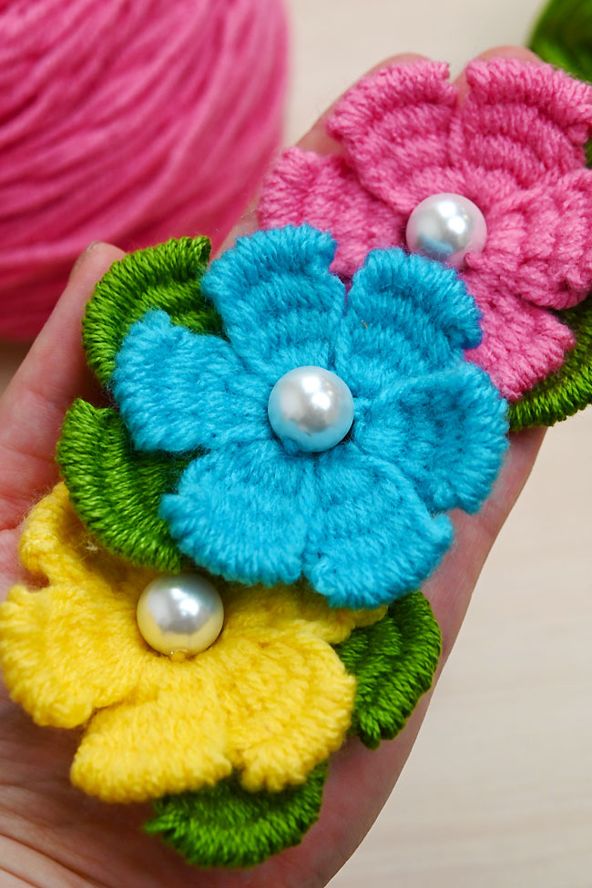Fork Yarn Flowers Closeup on blue, yellow, and pink flowers made from yarn