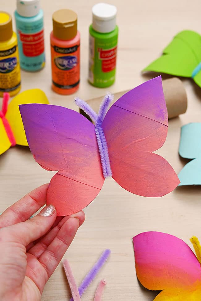Holding a pink and purple paper roll butterfly craft
