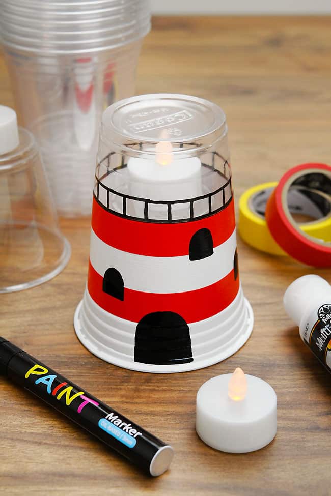 Plastic Cup Lighthouse Craft Closeup on a red and white striped lighthouse beside craft supplies to make one