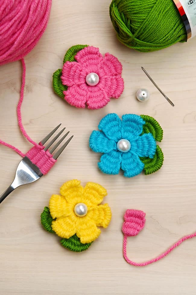 Yarn Flower with Fork Pretty yarn flower crafts on a wood background