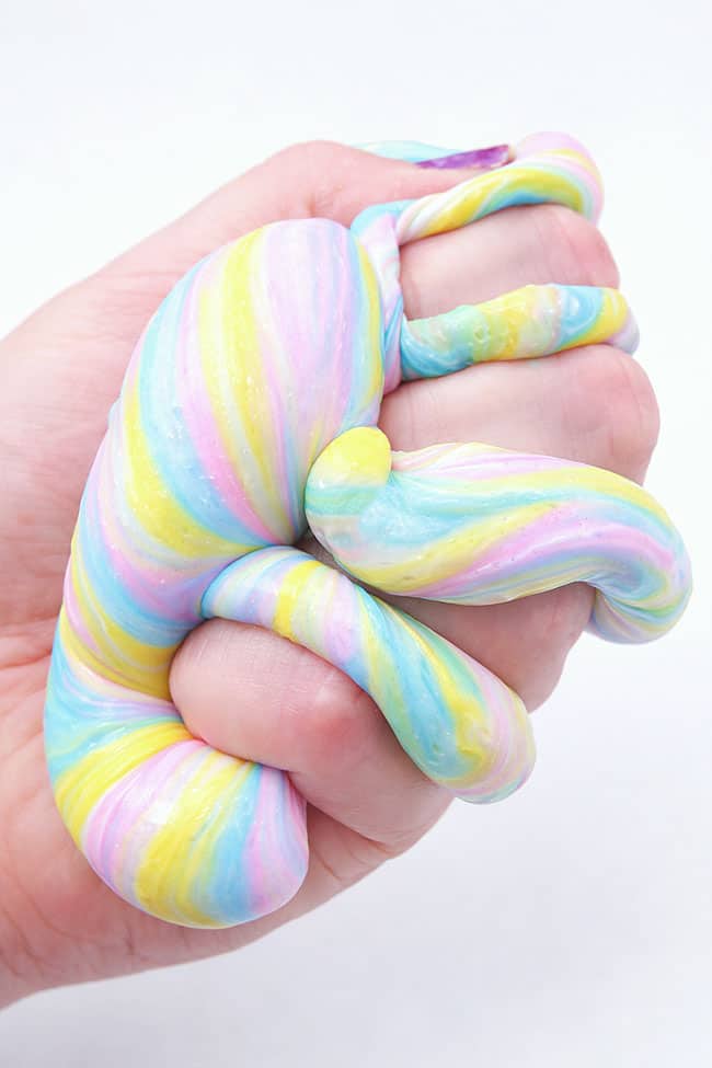 Squishing colourful unicorn slime in a hand