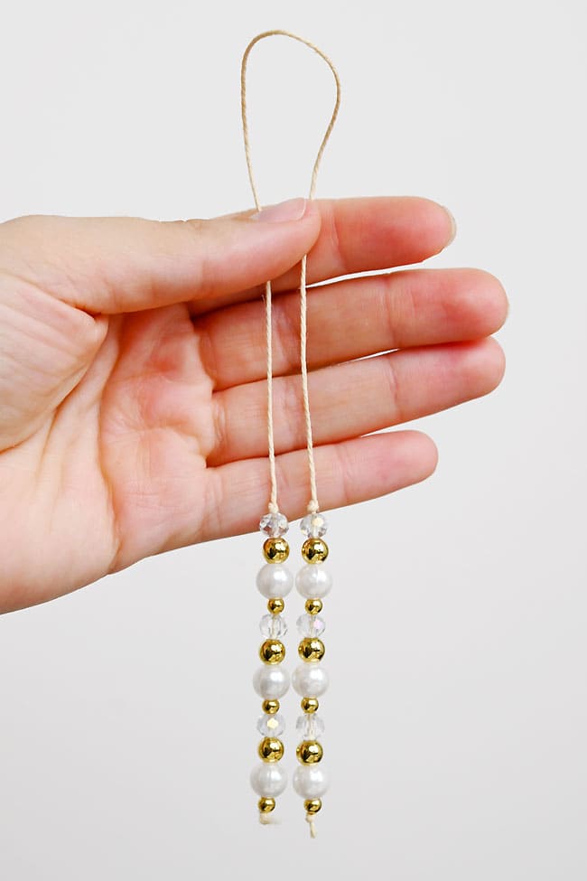 DIY Beaded Bookmarks Holding a DIY beaded bookmark with gold, pearl, and clear faceted beads