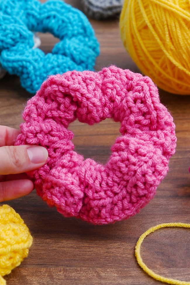 How to Make a Loom Knit Scrunchie Holding a pink loom knitted scrunchie