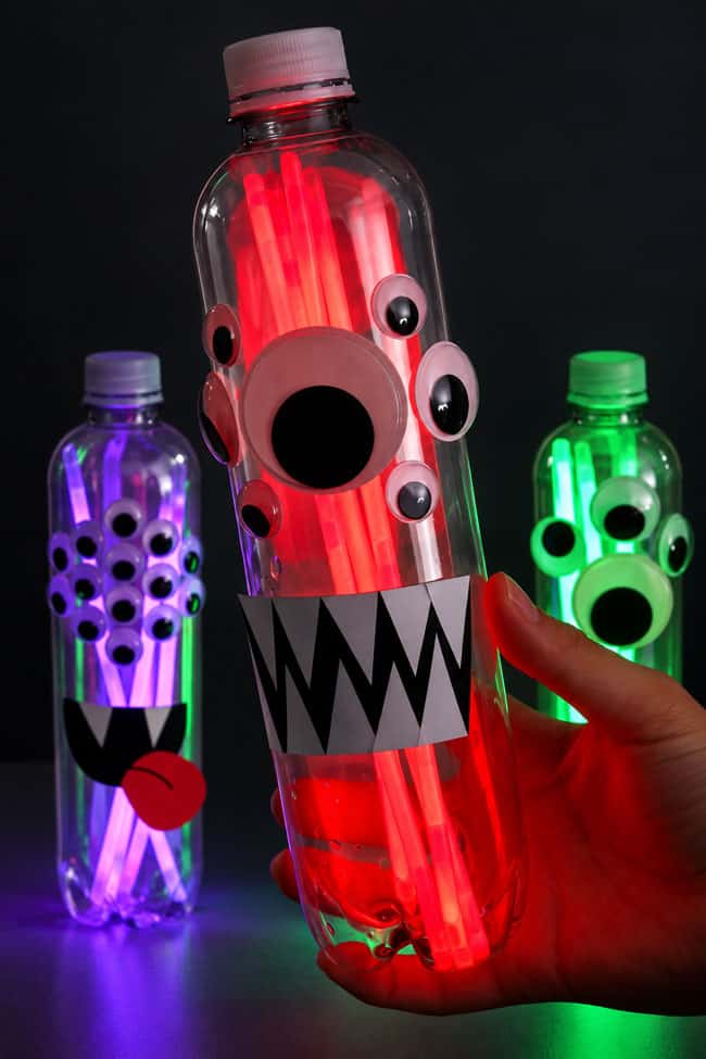 Glow Stick Lanterns Holding a monster lantern with red glow sticks, googly eyes, and paper fangs